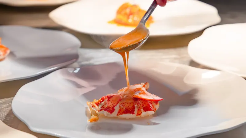 Sauce poured over a delicate seafood dish on a white plate