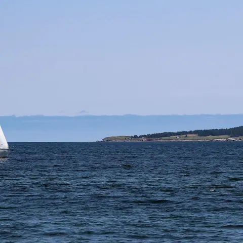 White sailboat on the open Atlantic near a headland