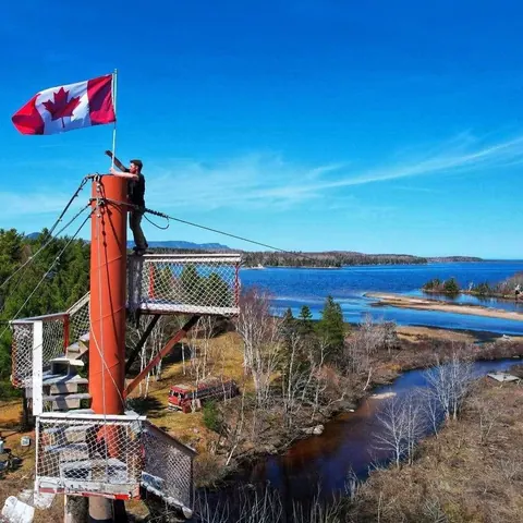 Zipline launch tower with a Canadian flag above the coast