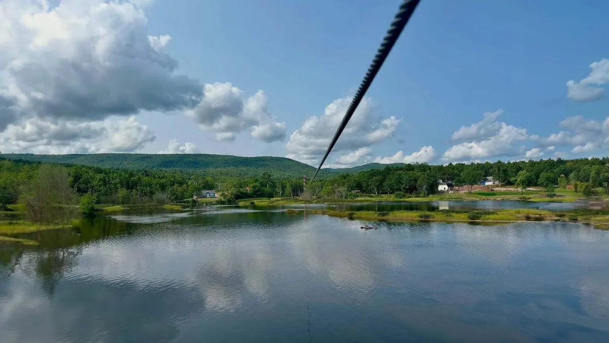 Zipline cable stretching over a lake and green hills