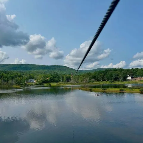 Zipline cable stretching over a lake and green hills